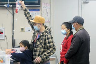A family member maintains an IV drip for the child amid increased HMPV